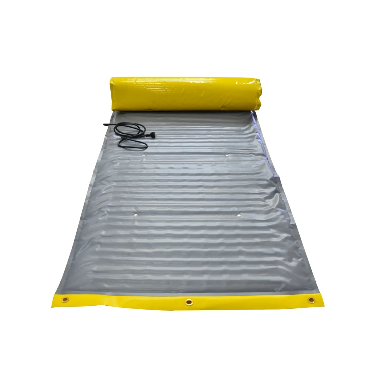 Partially unrolled ground-thawing blanket with yellow edges, metal eyelets, and a power cord.