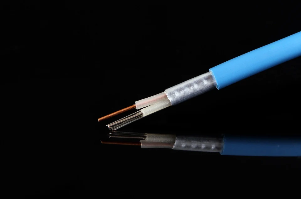 Blue heating cable cutaway showing insulation, metallic shielding, and exposed wires.