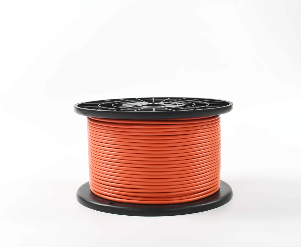 Orange underfloor heating cable wound on a black reel.